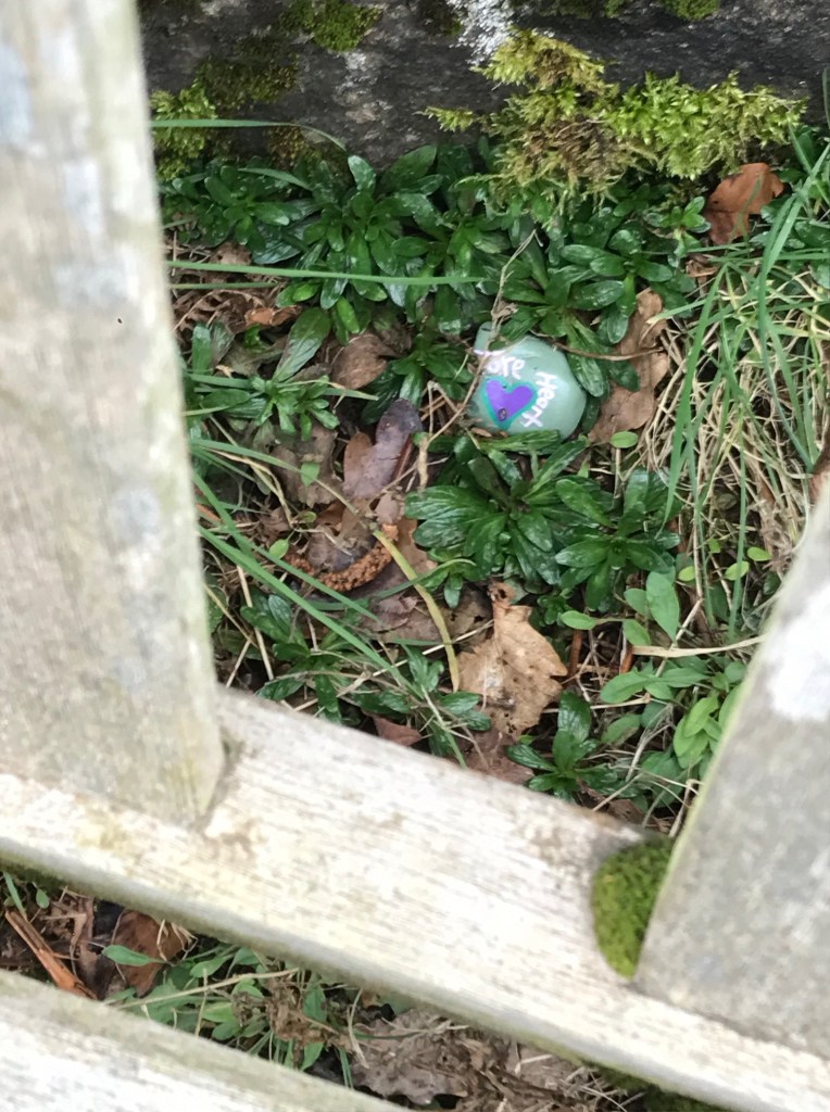 A small painted stone bearing the encouragement to "Take Heart."